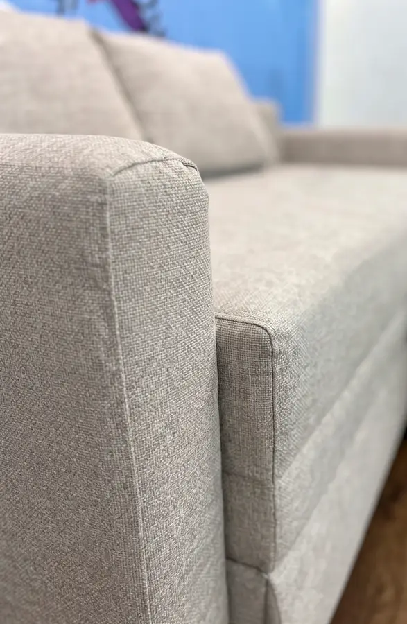 Primer plano de un sofá cama en tela Premium: costura del brazo y tramado tipo lino